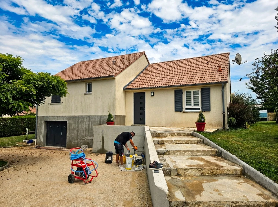 Ouvrier en combinaison de protection int&eacute;grale effectuant un sablage industriel en ext&eacute;rieur