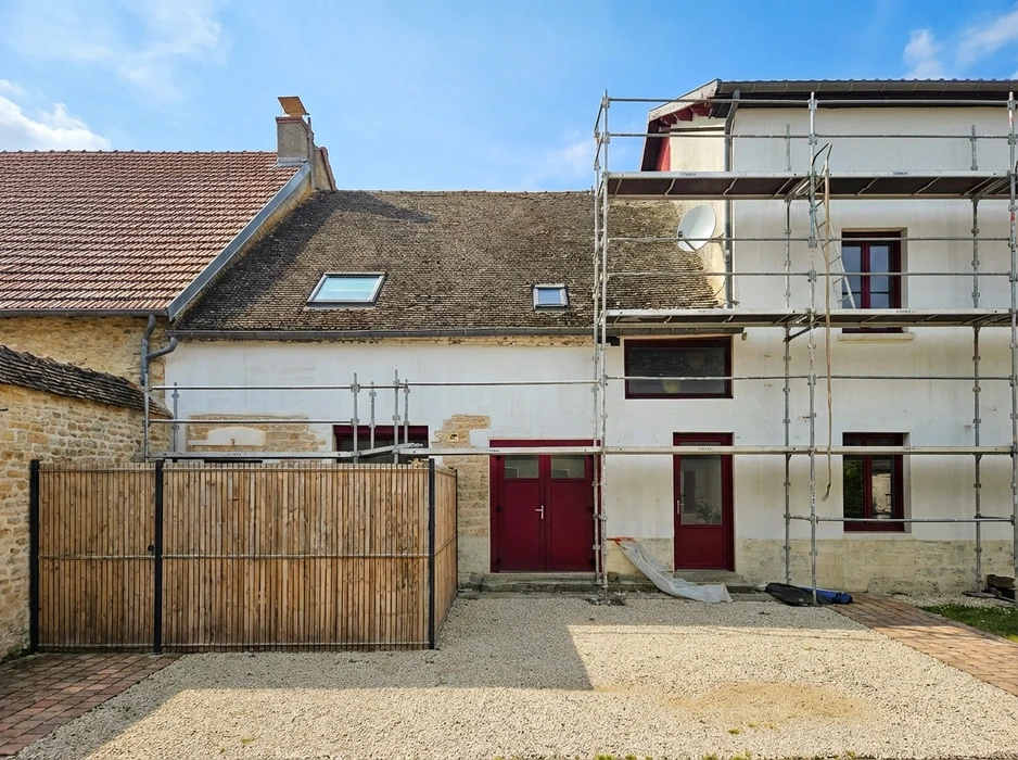 Gros plan professionnel d'une façade en brique ancienne partiellement nettoyée, montrant clairement la transition avant/après entre la surface encrassée et la surface restaurée par sablage sélectif. La texture de la brique et les joints sont nets et détaillés pour illustrer la précision du traitement appliqué selon le matériau.