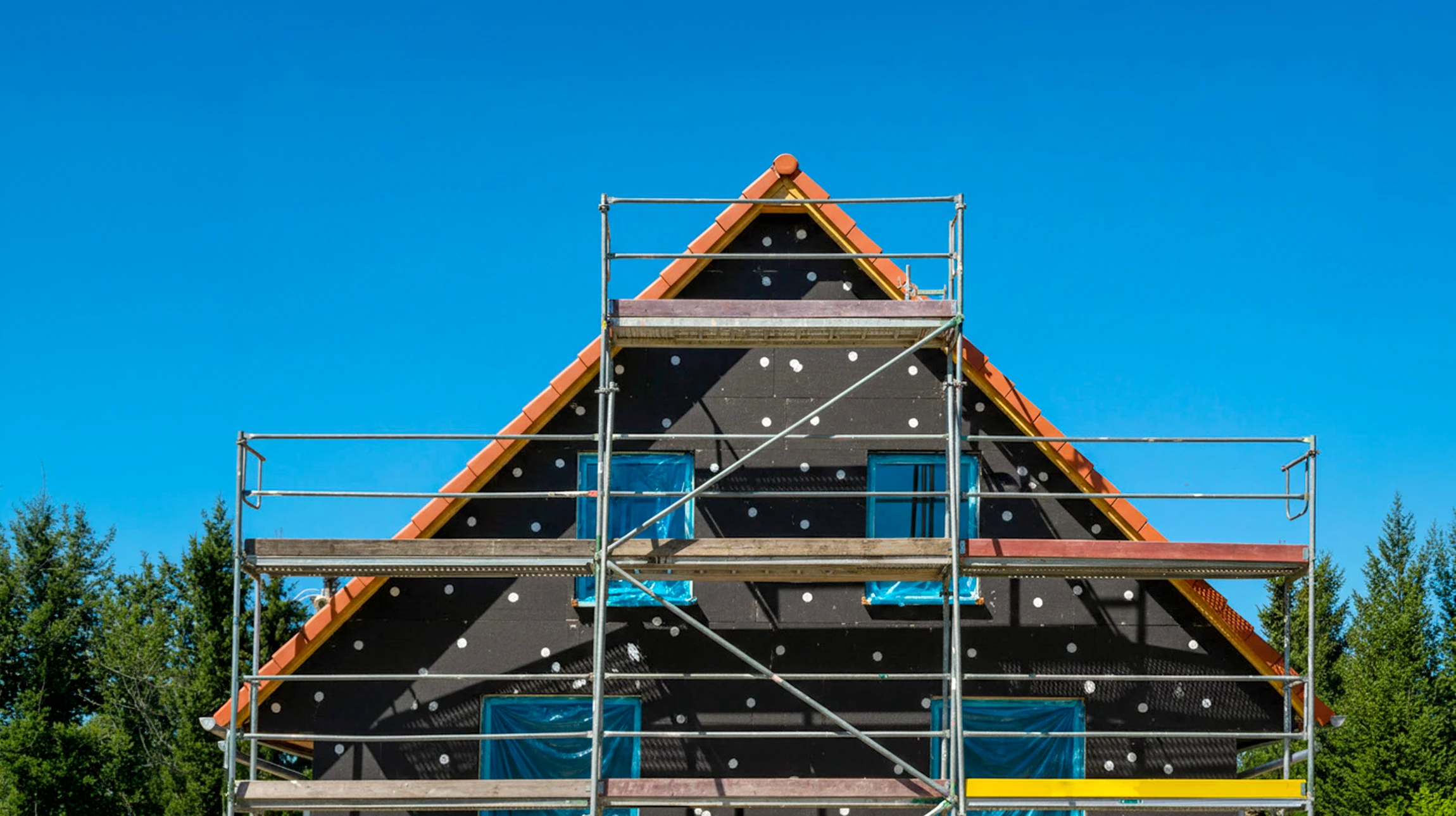 Chantier de rénovation de façade d'immeuble avec ouvrier travaillant sur échafaudage tubulaire métallique