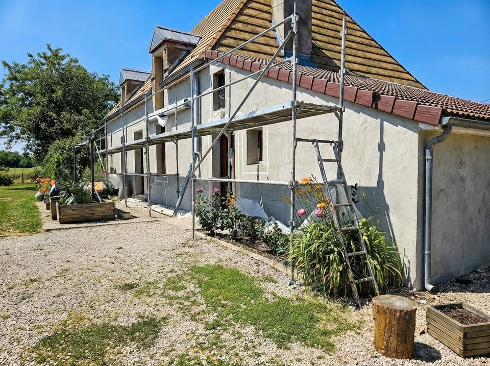 Scène extérieure montrant un mur en briques rouges anciennes avec joints blancs, présentant des traces d'humidité et de vieillissement